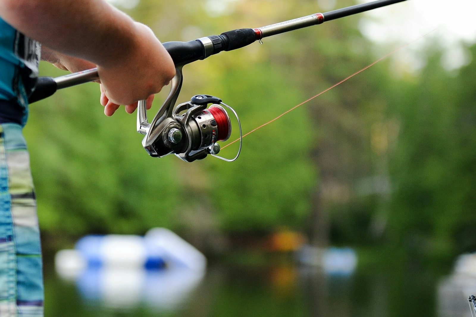 Caña y carrete de spinning en las manos de un pescador