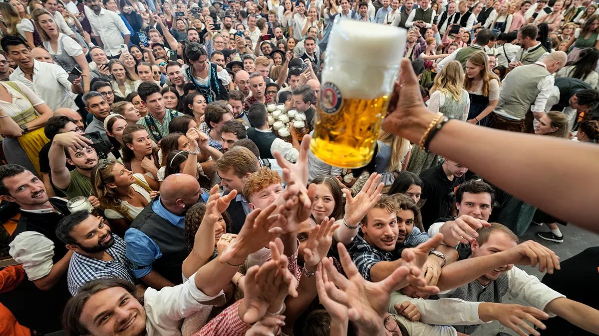 Multitud levantando las manos hacia un jarro de cerveza en una fiesta de la cerveza