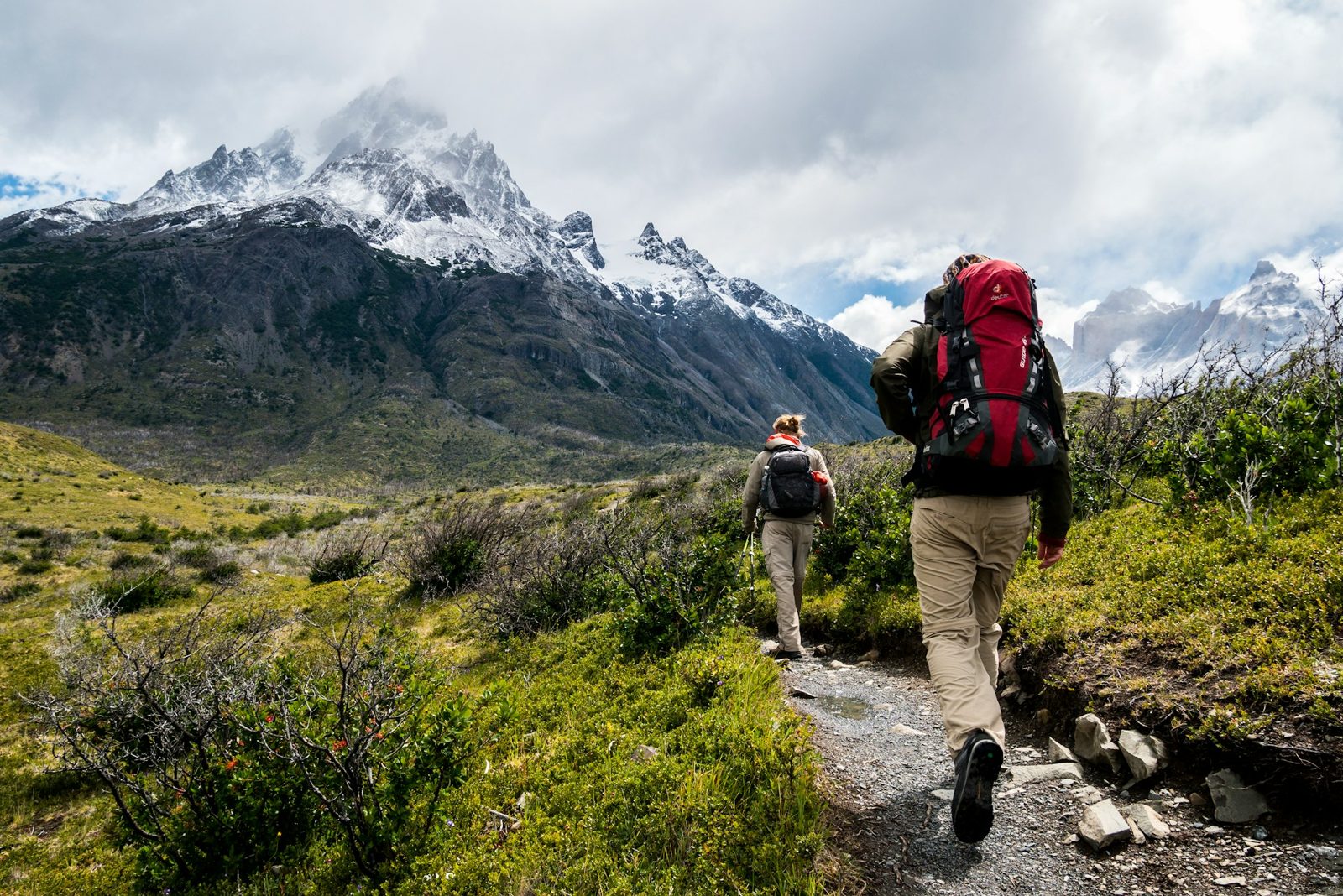 Dos senderistas caminan hacia montañas nevadas en la Patagonia